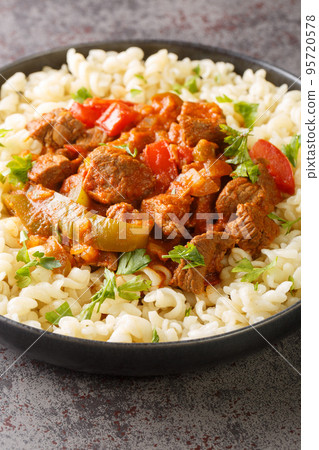 Porkolt is a classic Hungarian cuisine beef stew with onions and plenty of paprika close-up in a plate. Vertical 95720578