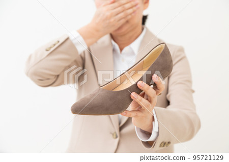 A middle-aged woman in a suit who stinks of pumps and pinches her nose 95721129