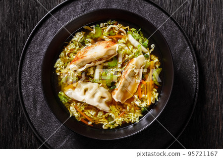 Asian Potstickers Soup in black bowl, top view 95721167