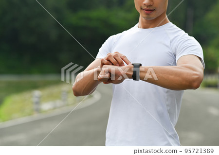 Sportsman resting after jogging and checking his heart rate data on smartwatch. Healthy lifestyle, workout and wellness concept 95721389