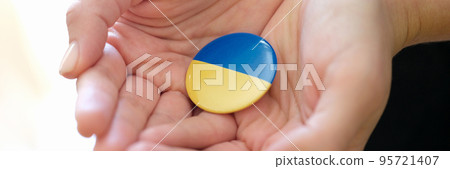 Female hands holding badge with flag of Ukraine closeup Female hands holding badge with flag of Ukraine closeup 95721407