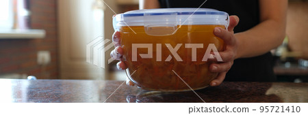 Housewife holding plastic container with soup in her hands closeup Housewife holding plastic container with soup in her hands closeup 95721410