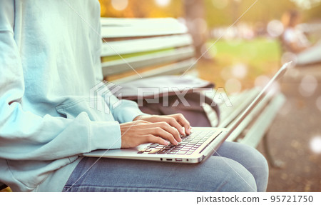 Man writing notebook with laptop in the park vintage style, Slim hipster man in jeans using a notebook, Freelancers, communication, Teenage student boy browses the Internet, working outside the home Man writing notebook with laptop in the park vintage style, Slim hipster man in jeans using a notebook, Freelancers, communication, Teenage student boy browses the Internet, working outside the home 95721750