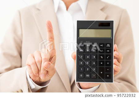 一位穿著西裝的中年婦女拿著計算器,舉起食指 一位穿著西裝的中年婦女拿著計算器,舉起食指 95722032