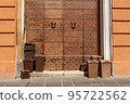 Brown plastic bins with biological waste on the sidewalk in front of a historic old wooden door. 95722562