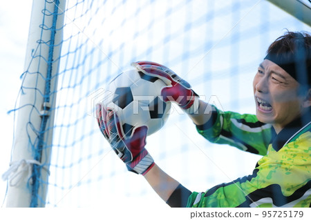 Goalkeeper man catching a soccer ball 95725179