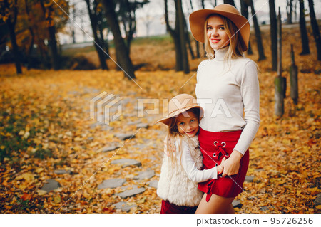 Fashionable mother with daughter. Family in a autumn park. 95726256