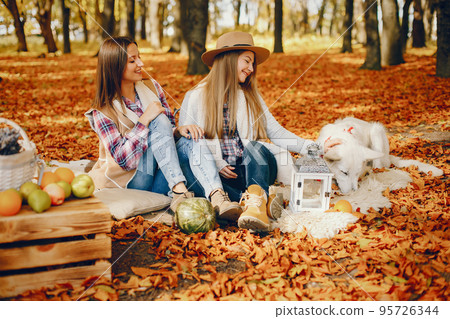 Beautiful girls in a park. Cute ladies in a stylish clothes. Friends with cute dog Beautiful girls in a park. Cute ladies in a stylish clothes. Friends with cute dog 95726344