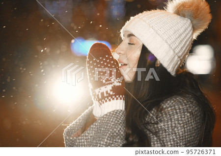 Winter holidays conception. Outdoor night portrait of young girl. Posing in street of European city. 95726371