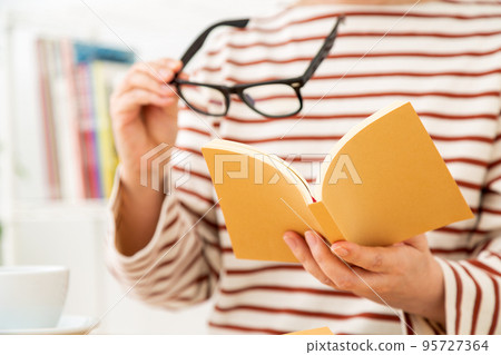 手拿眼鏡看書的休閒中年婦女 95727364