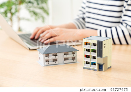 A middle-aged woman who operates a personal computer in the room and a house model 95727475