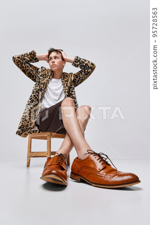 Portrait of stylish teen boy in animal print jacket and classic brogue shoes posing isolated on grey background. Unique style Portrait of stylish teen boy in animal print jacket and classic brogue shoes posing isolated on grey background. Unique style 95728563