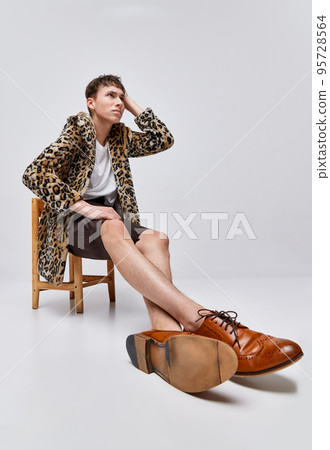 Portrait of stylish teen boy in animal print jacket and classic brogue shoes posing emotively isolated on grey background Portrait of stylish teen boy in animal print jacket and classic brogue shoes posing emotively isolated on grey background 95728564
