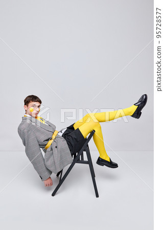 Portrait of stylish boy posing in jacket, blazer and yellow tights isolated over grey background. Casual and bright 95728577