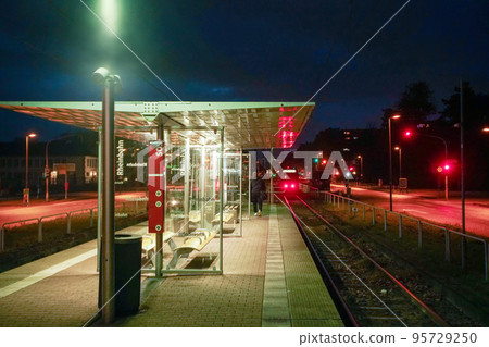 Stop next to the Nordpark in Dusseldorf - very bright red lights from the train and cars and lights on the street 95729250