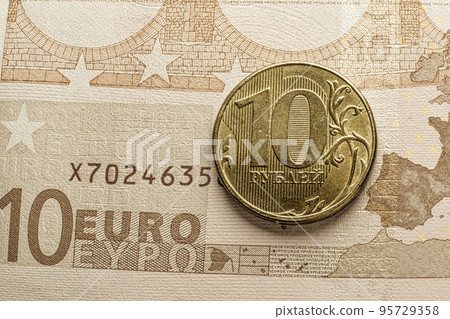 Golden RUR russian ruble coin over euro banknote macro image - depicting EU economy crisis and recession by sanctions agains Russia Golden RUR russian ruble coin over euro banknote macro image - depicting EU economy crisis and recession by sanctions agains Russia 95729358