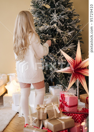 Attractive young woman stand in front of Christmas tree. Winrter holiday mood 95729410
