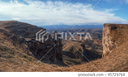 Amazing view of Bermamyt plateau rocks on sunny day. Caucasus Mountains on the edge of a cliff in the distance. Atmospheric landscape with silhouettes of mountains. Karachay-Cherkessia, Russia. 95729768