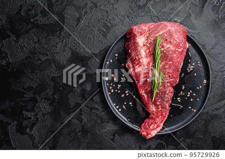 Seasoned raw tri-tip beef meat steak on plate. Black background. Top view. Copy space Seasoned raw tri-tip beef meat steak on plate. Black background. Top view. Copy space 95729926