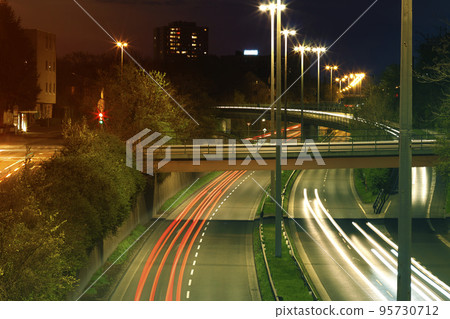 Freeway with urban night traffic with focusing on the road. Car trails on a highway Freeway with urban night traffic with focusing on the road. Car trails on a highway 95730712