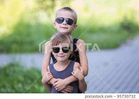 Two children in black sunglasses having fun time outdoors in summer. 95730732
