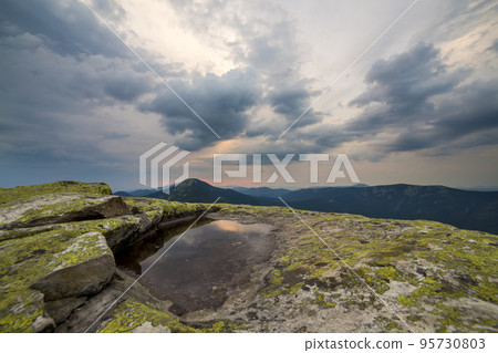 Blue sky reflected in small lake on rocky mountain peak on blue mountain range background at dawn. Blue sky reflected in small lake on rocky mountain peak on blue mountain range background at dawn. 95730803