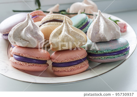 Sweet and colorful french macaroons or macaron in ceramic white plate. Pastel colours. Selective soft focus. Sweet and colorful french macaroons or macaron in ceramic white plate. Pastel colours. Selective soft focus. 95730937