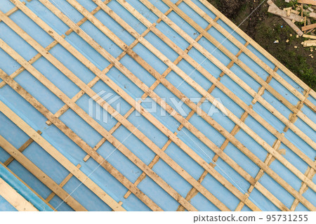 Aerial view of a brick house with wooden roof frame under construction. Aerial view of a brick house with wooden roof frame under construction. 95731255