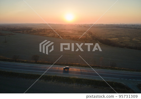 Aerial view of intercity road with blurred fast driving car at sunset. Top view from drone of highway traffic in evening Aerial view of intercity road with blurred fast driving car at sunset. Top view from drone of highway traffic in evening 95731309