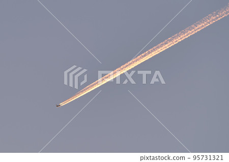 Distant passenger jet plane flying on high altitude on clear blue sky leaving white smoke trace of contrail behind. Air transportation concept 95731321