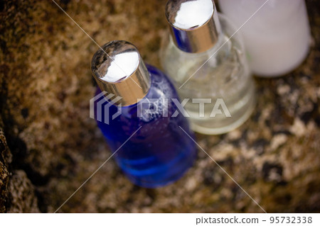 Plastic bottles with natural cosmetic in travel containers - blue shower gel, shampoo with bubbles inside, body lotion in miniature containers against a brown stone rock background. Face body care. Plastic bottles with natural cosmetic in travel containers - blue shower gel, shampoo with bubbles inside, body lotion in miniature containers against a brown stone rock background. Face body care. 95732338