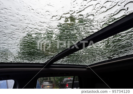Inside a vehicle looking up to a sunroof with water droplets Inside a vehicle looking up to a sunroof with water droplets 95734120