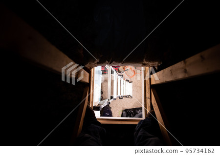 Looking down through the access opening to an attic with the ladder underneath Looking down through the access opening to an attic with the ladder underneath 95734162