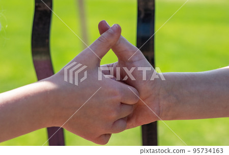 Two children playing a thumb war battle with the objective to pin the opposing player's thumb Two children playing a thumb war battle with the objective to pin the opposing player's thumb 95734163