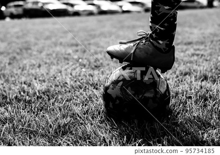 Selective focus on girls' soccer ball with a player on the grass field.  95734185