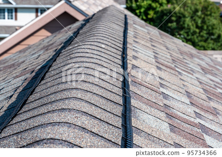 Ridge cap vent installed on a shingle roof for passive attic ventilation on a residential house. Ridge cap vent installed on a shingle roof for passive attic ventilation on a residential house. 95734366