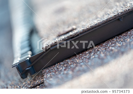 Ridge cap vent installed on a shingle roof for passive attic ventilation on a residential house. Ridge cap vent installed on a shingle roof for passive attic ventilation on a residential house. 95734373