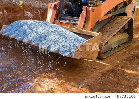 An excavator bucket rakes in crushed stone the excavator is picking up a full bucket of gravel 95735106