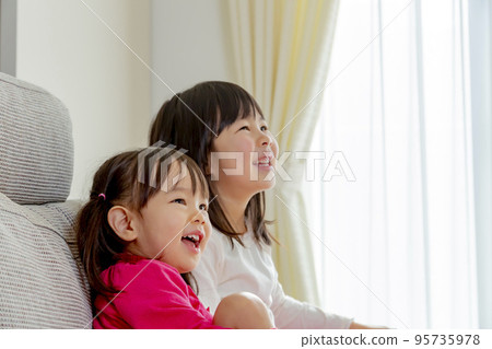 Sisters laughing in the living room 95735978