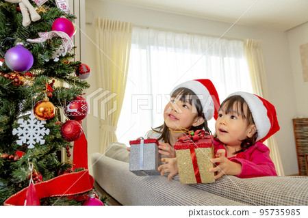 Sisters playing next to the Christmas tree 95735985