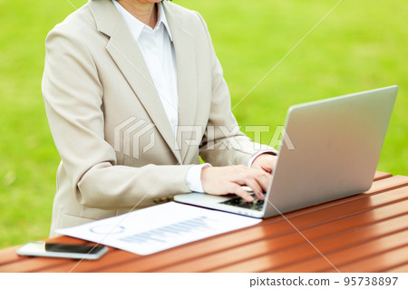 A middle-aged woman in a suit looking at graph materials in an outdoor park A middle-aged woman in a suit looking at graph materials in an outdoor park 95738897