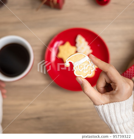 Merry Christmas with woman hand holding coffee cup and homemade cookie on table. Xmas eve, party, holiday and happy New Year concept Merry Christmas with woman hand holding coffee cup and homemade cookie on table. Xmas eve, party, holiday and happy New Year concept 95739322