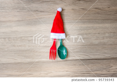 Merry Christmas with miniature Santa Claus, fork and spoon on wood table background. Xmas, party and happy New Year concept Merry Christmas with miniature Santa Claus, fork and spoon on wood table background. Xmas, party and happy New Year concept 95739343