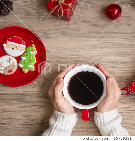 Merry Christmas with woman hand holding coffee cup and homemade cookie on table. Xmas eve, party, holiday and happy New Year concept Merry Christmas with woman hand holding coffee cup and homemade cookie on table. Xmas eve, party, holiday and happy New Year concept 95739351