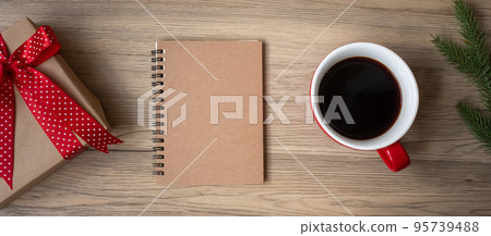Blank notebook, black coffee cup and Christmas gift on wood table, Top view and copy space. Xmas, Happy New Year, Goals, Resolution, To do list, Strategy and Plan concept 95739488