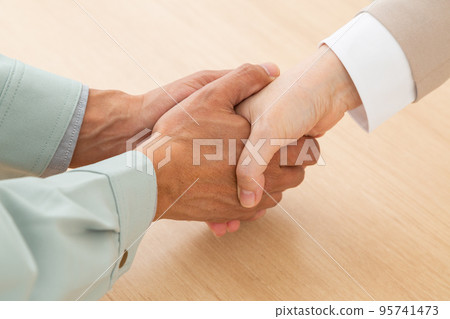 A man in work clothes and a woman in a suit shaking hands A man in work clothes and a woman in a suit shaking hands 95741473