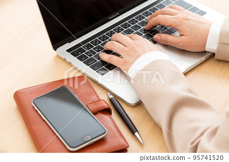 A middle-aged woman wearing a suit operating a personal computer in the office A middle-aged woman wearing a suit operating a personal computer in the office 95741520
