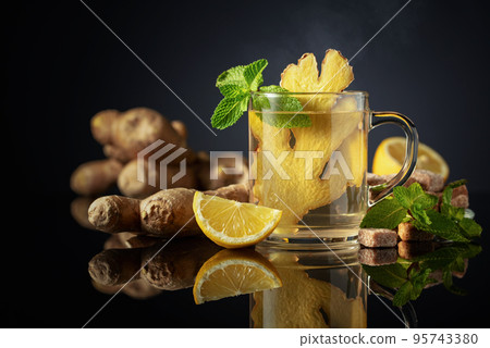 Ginger tea with lemon and mint  on a black reflective background. 95743380