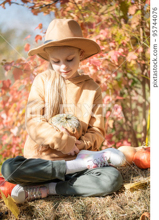 Girl in the hay with pumpkins Girl in the hay with pumpkins 95744076