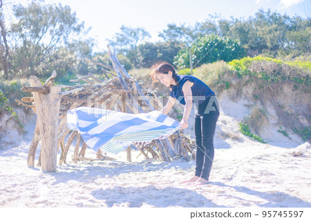 Woman spreading a beach towel on the beach Woman spreading a beach towel on the beach 95745597